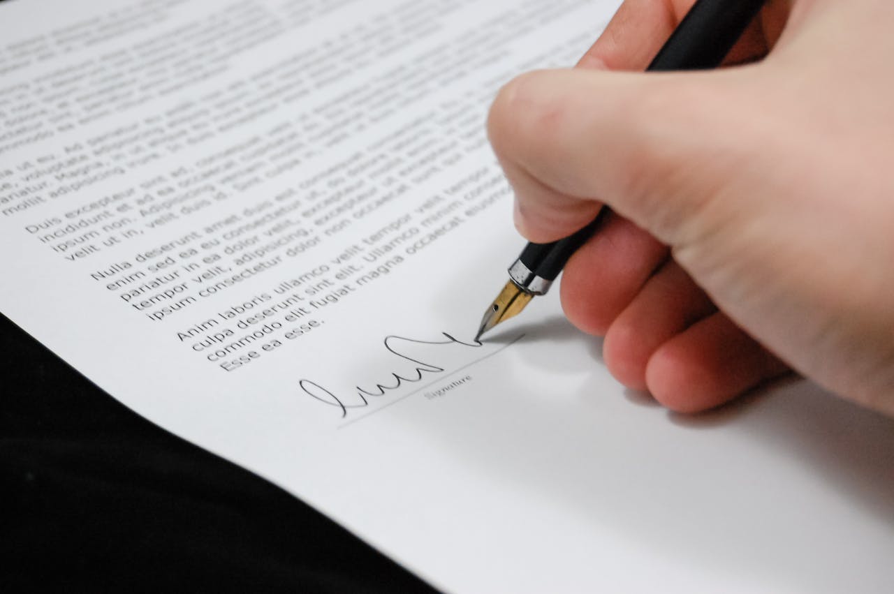 Close-up of a hand signing a legal document with a fountain pen, symbolizing signature and agreement.