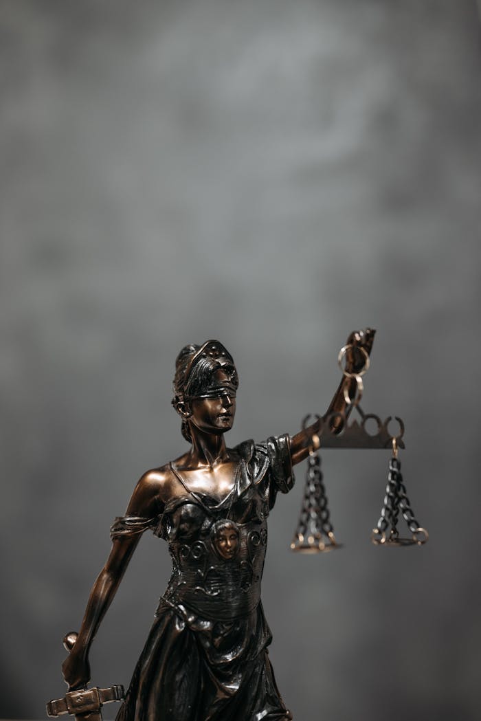 Close-up of a bronze Lady Justice statue holding scales, symbolizing law and fairness.